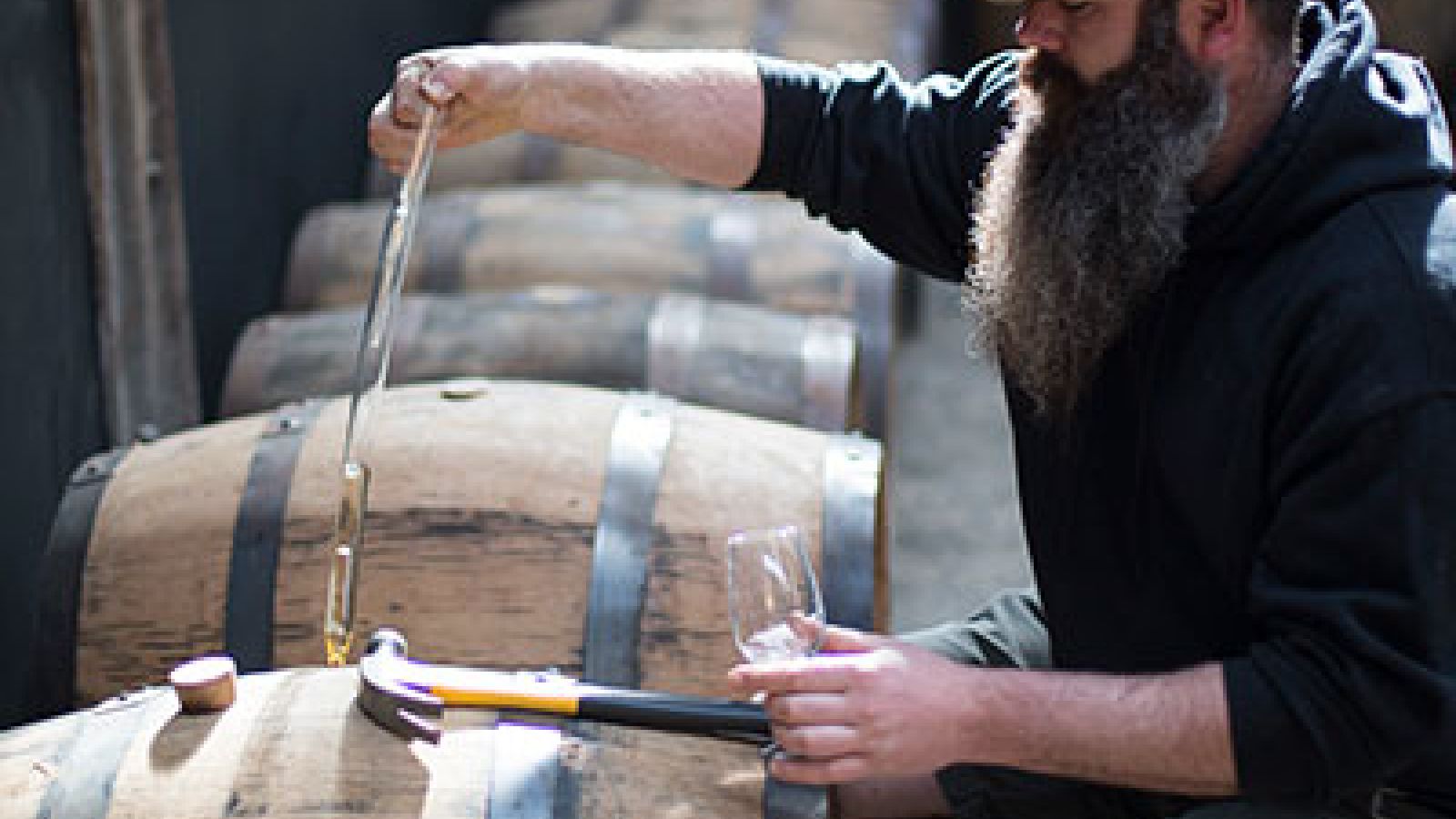 Photo of a worker taking a sample from an oak barrel; ©2016, Bill Bradshaw Photography