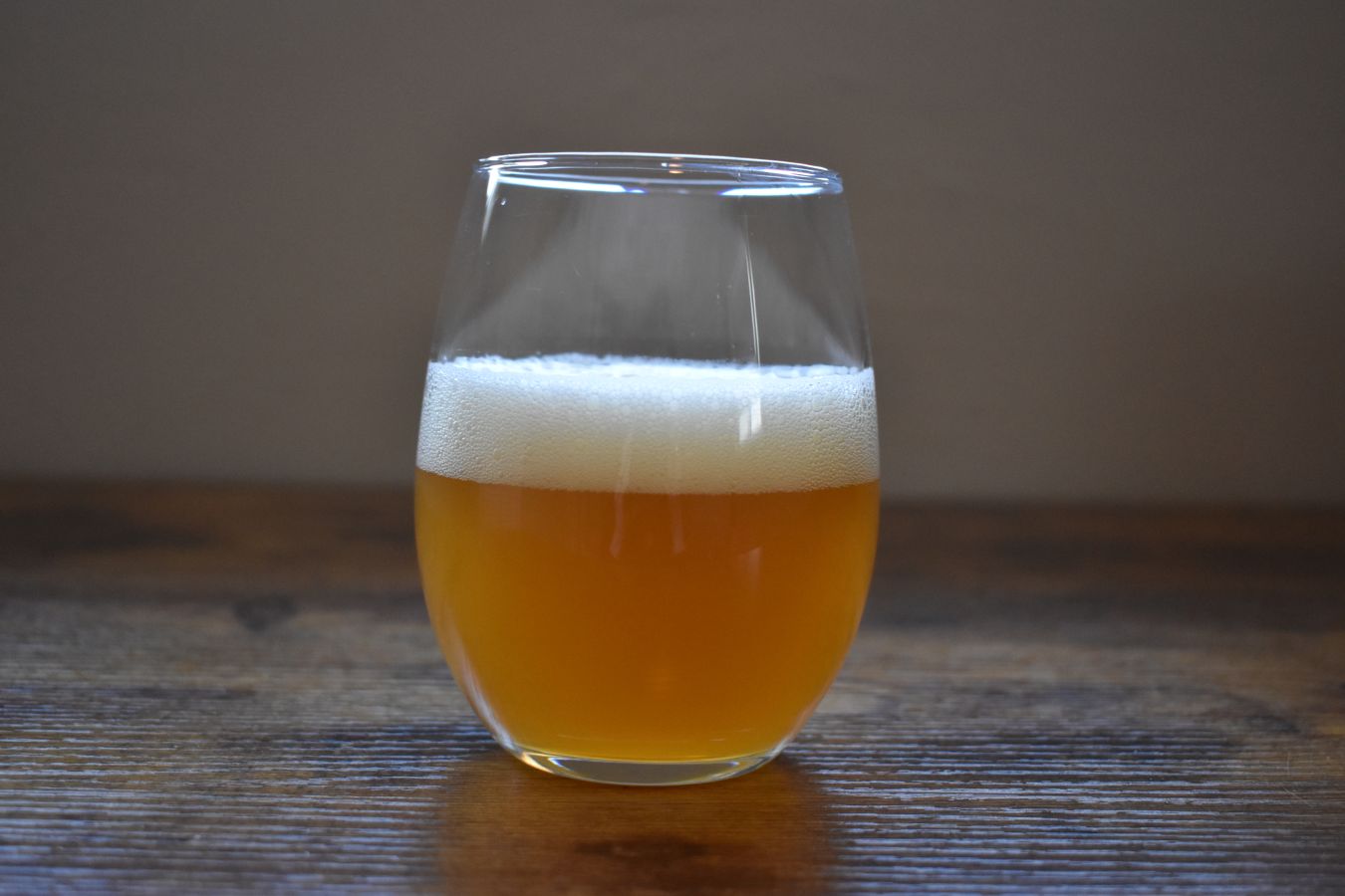 Photo of a small glass of White IPA placed on a wooden table; ©2022, Hollie Stephens Photography