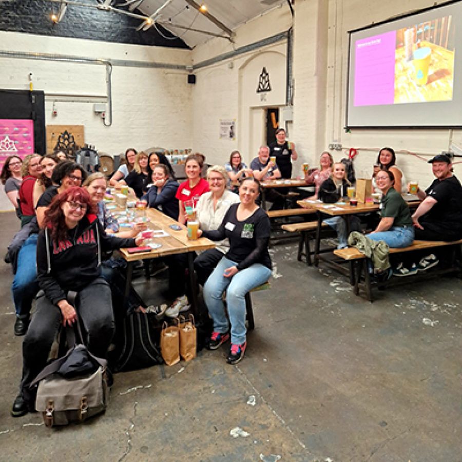 Photo of women gathered around a table, smiling at the camera, at a IWCBD event © 2025, Laura Hadland Photography