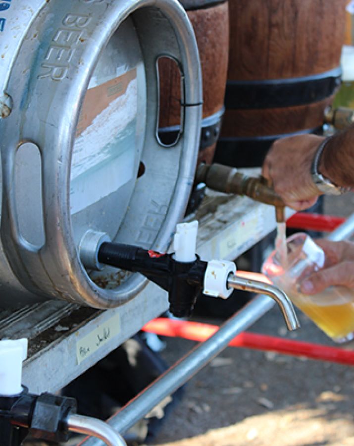 Photo of a container of cask beer with someone pouring a glass of beer behind © 2024, Justin Brummer