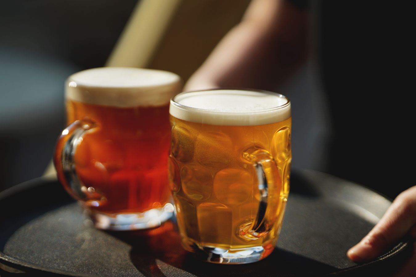 Two handled and dimpled beer glasses filled with beer on mat © Matthew Curtis