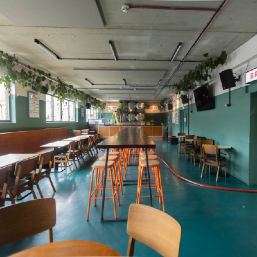 Photo of the inside of a taproom with tables, cans and kegs © Bill Bradshaw